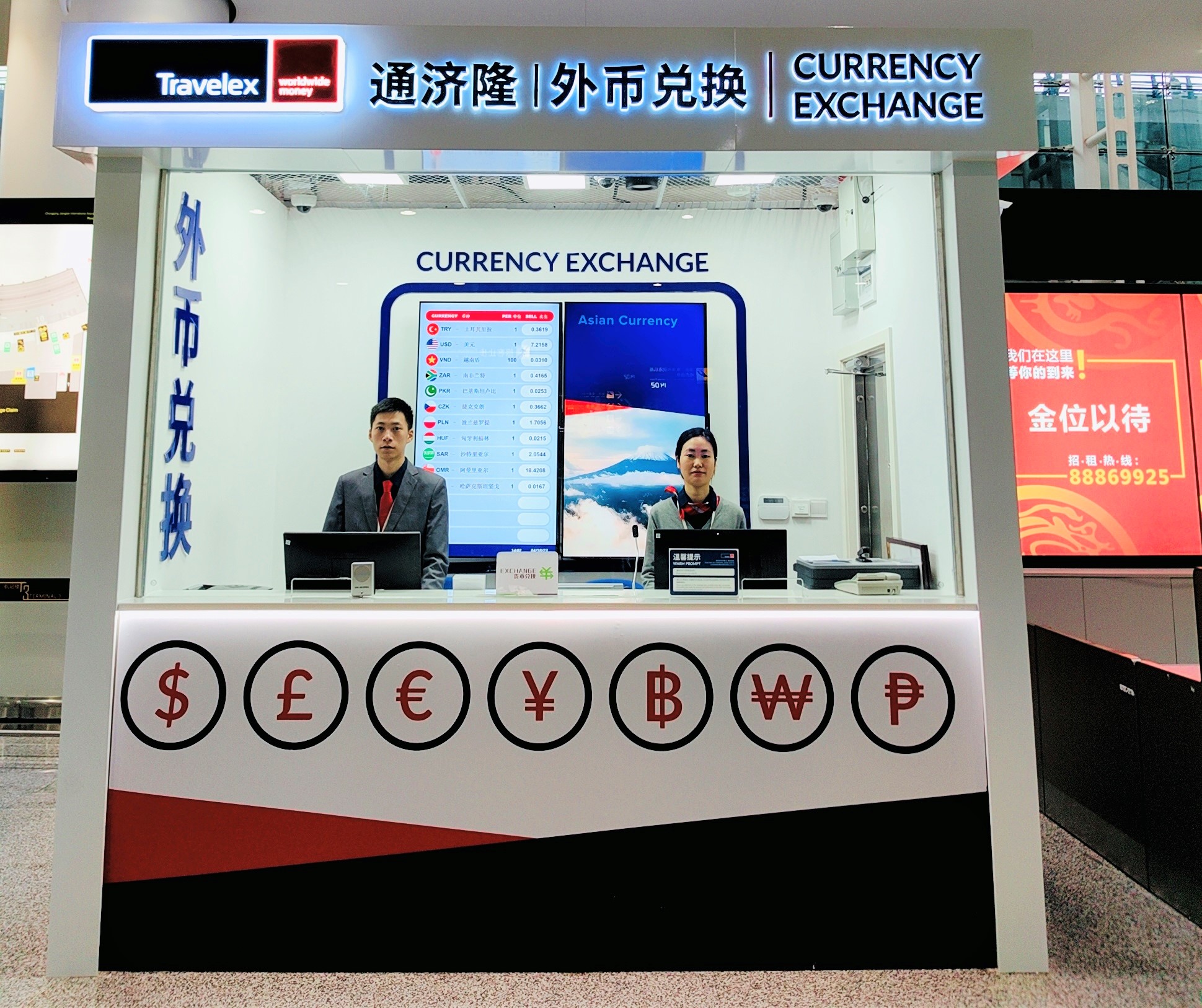 Man and woman sitting inside Travelex branded currency exchange booth